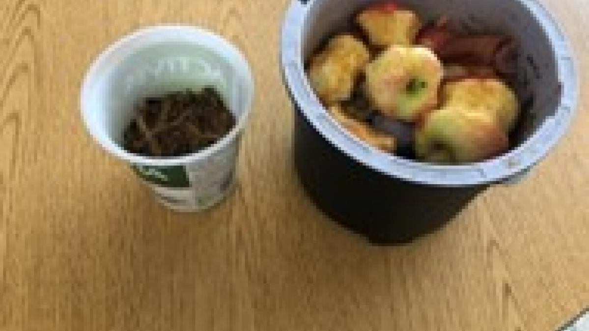 Round containers with food scraps in them on faux-wood table.