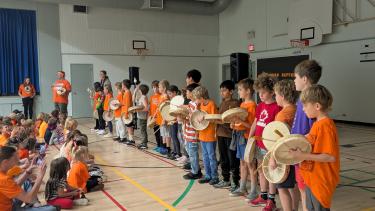 students performing a drum song at an assembly