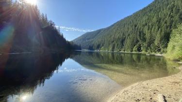 A calm mountain lake with a sandy shore on a sunny day
